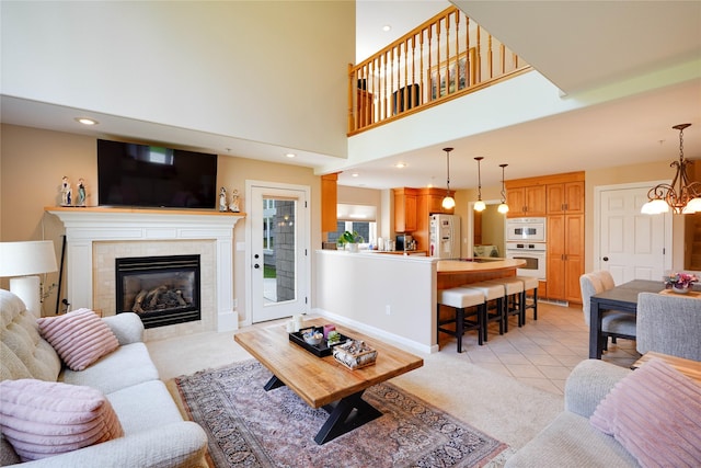 living room featuring light tile patterned flooring, a towering ceiling, a fireplace, and a chandelier