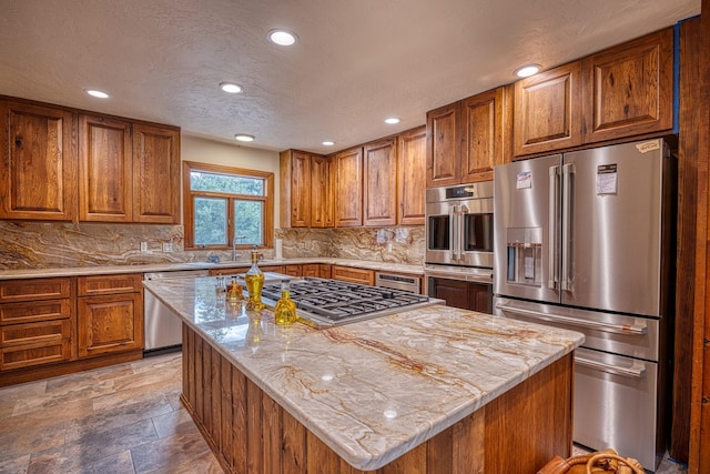 kitchen with decorative backsplash, a kitchen island, light stone countertops, and appliances with stainless steel finishes