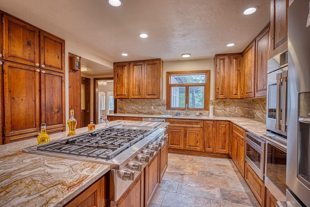 kitchen with tasteful backsplash, light stone counters, a textured ceiling, stainless steel gas cooktop, and oven