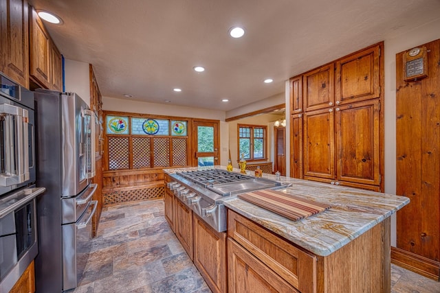 kitchen with a center island, light stone counters, and appliances with stainless steel finishes