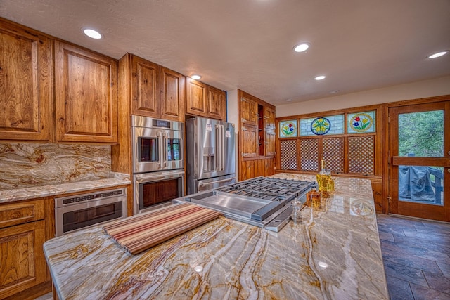 kitchen with appliances with stainless steel finishes, tasteful backsplash, and light stone counters