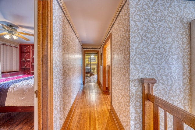corridor with light hardwood / wood-style floors and crown molding