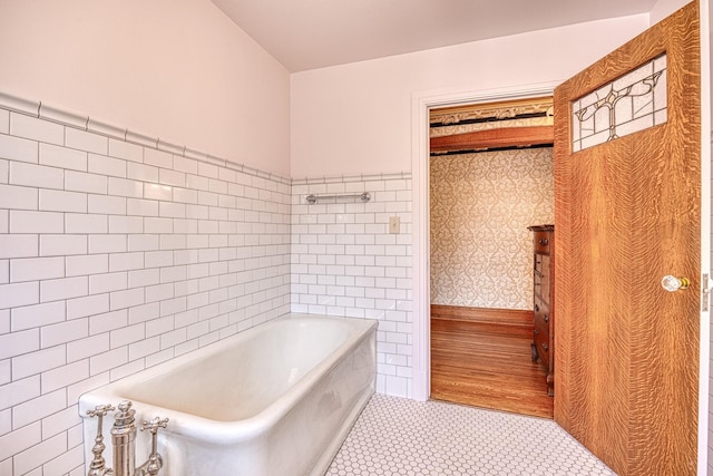 bathroom featuring tile patterned floors, a tub to relax in, and tile walls
