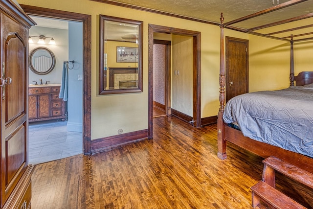 bedroom featuring ensuite bathroom, dark hardwood / wood-style floors, ornamental molding, and a textured ceiling