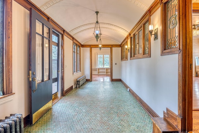 hall featuring radiator heating unit, vaulted ceiling, and brick ceiling