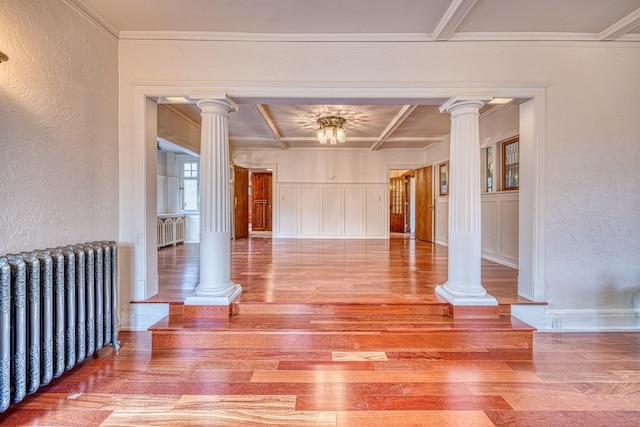 unfurnished room featuring radiator heating unit, coffered ceiling, crown molding, and wood-type flooring