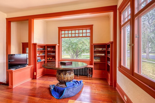 office space with a wealth of natural light, radiator heating unit, crown molding, and hardwood / wood-style flooring