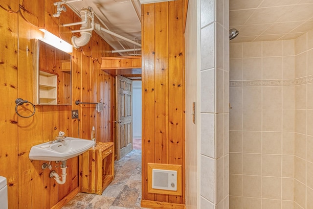 bathroom featuring toilet, wooden walls, and sink