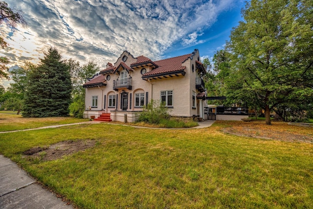 mediterranean / spanish-style home with a yard and a balcony