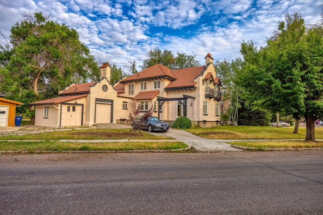 mediterranean / spanish house featuring a garage and a front lawn