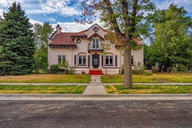 view of front of house with a balcony and a front lawn