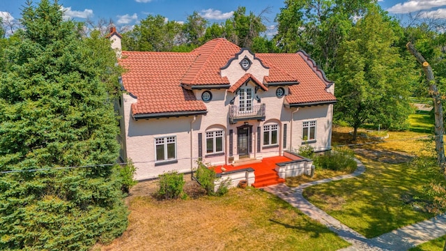 view of front of house featuring a balcony and a front lawn