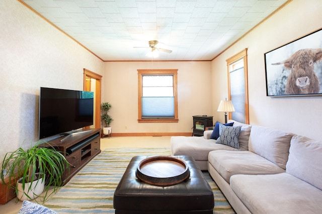 carpeted living room with a wood stove, ceiling fan, and ornamental molding