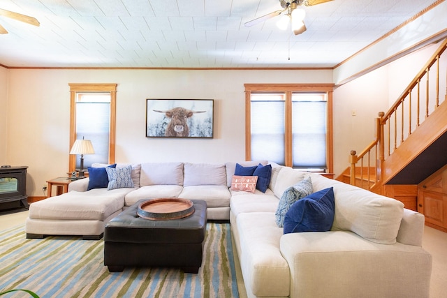 carpeted living room featuring a wood stove, crown molding, and ceiling fan