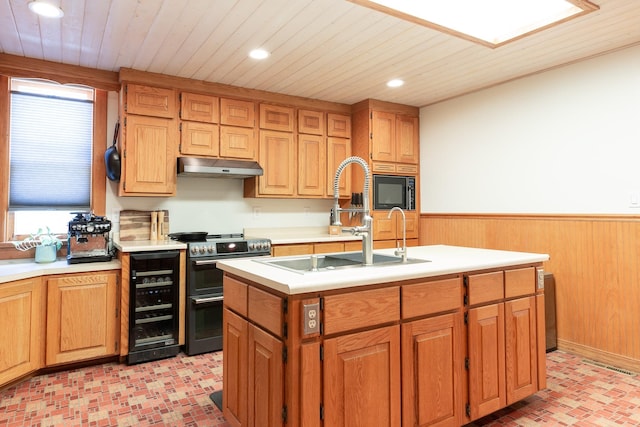 kitchen featuring sink, beverage cooler, wood walls, stainless steel range with electric stovetop, and a kitchen island with sink