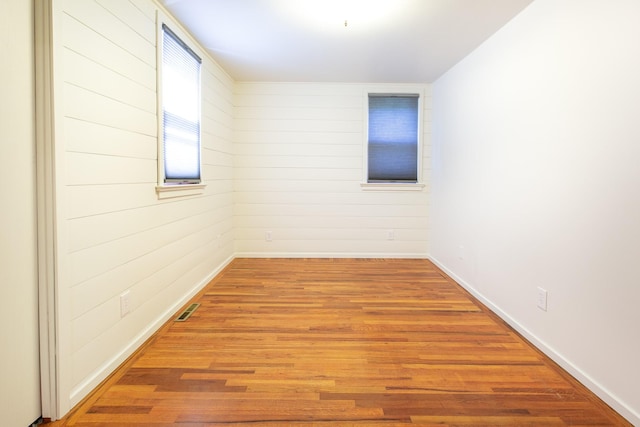 empty room featuring wood-type flooring and wooden walls