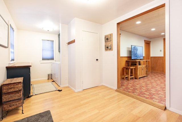 foyer with washer / dryer, light hardwood / wood-style floors, and wood walls