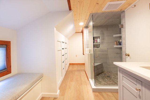 bathroom with vanity, hardwood / wood-style flooring, vaulted ceiling, and a shower with shower door