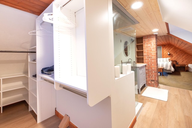 spacious closet featuring light hardwood / wood-style floors and lofted ceiling