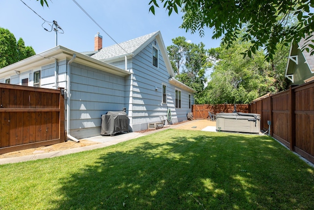 rear view of house featuring a patio area, a yard, and a hot tub