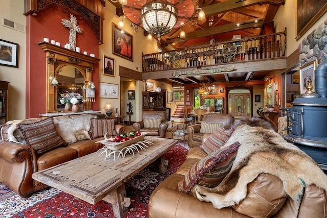 living room with a wood stove, a towering ceiling, and a chandelier