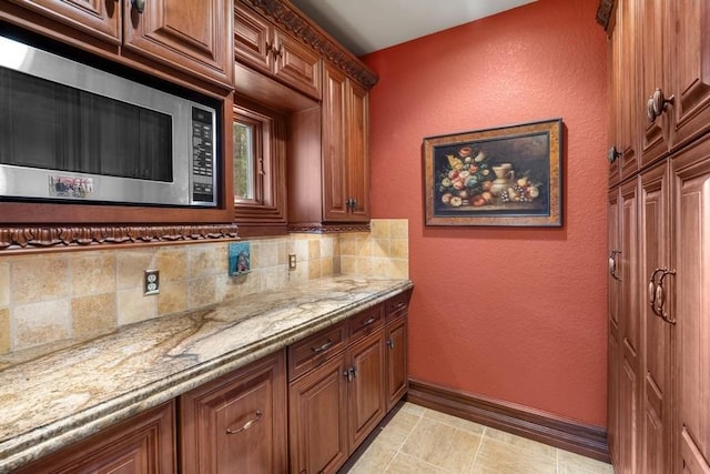 bar with decorative backsplash, stainless steel microwave, and light stone counters