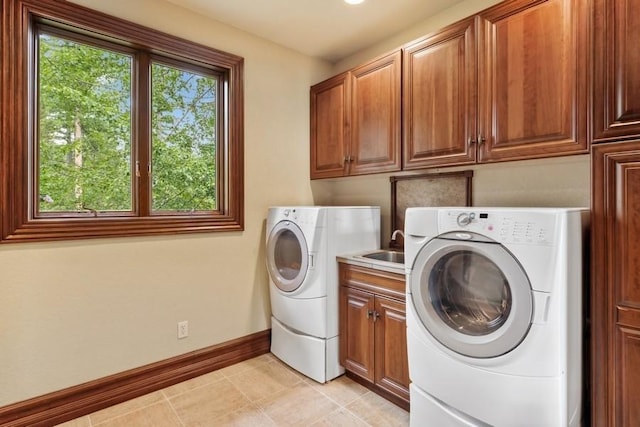 laundry area featuring cabinets, light tile patterned floors, sink, and washing machine and clothes dryer