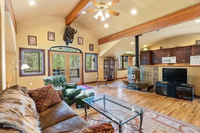 living room with a wood stove, ceiling fan, french doors, light hardwood / wood-style flooring, and lofted ceiling with beams