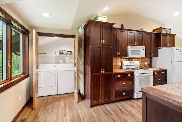 kitchen featuring separate washer and dryer, backsplash, light hardwood / wood-style floors, vaulted ceiling, and white appliances