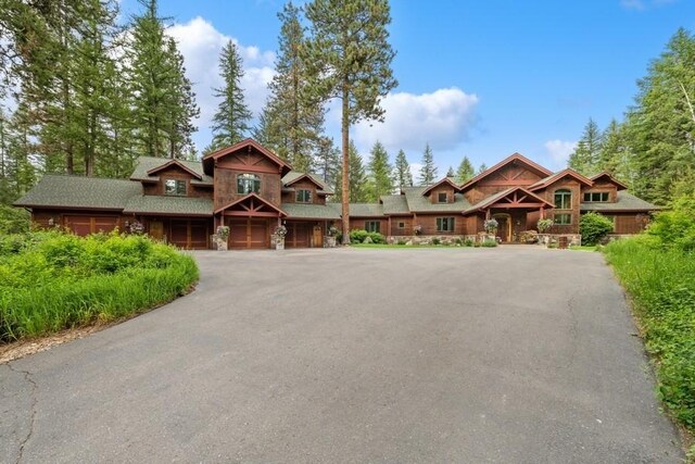 940 Mccaffery Rd, Bigfork, MT 59911 - chalet / cabin featuring asphalt driveway and stone siding