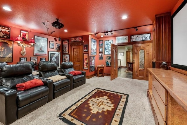 carpeted home theater with a textured ceiling and track lighting