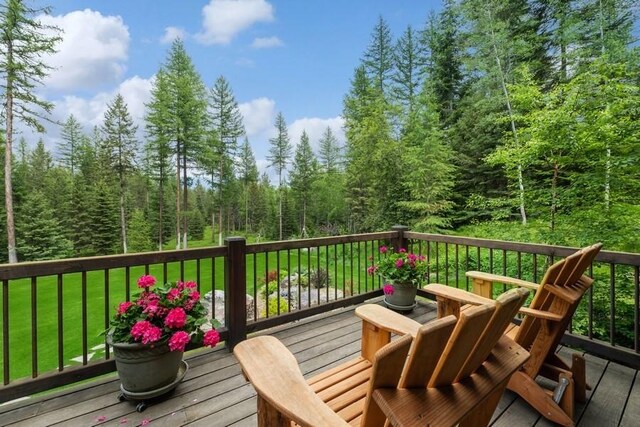940 Mccaffery Rd, Bigfork, MT 59911 - wooden deck featuring a forest view and a lawn