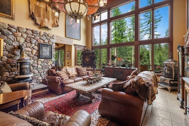 living room with plenty of natural light, a wood stove, a high ceiling, and a chandelier