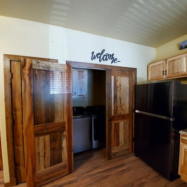 kitchen with washer and clothes dryer, light brown cabinetry, black refrigerator, and dark hardwood / wood-style floors