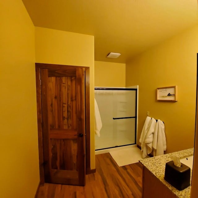 bathroom with hardwood / wood-style flooring, vanity, and walk in shower