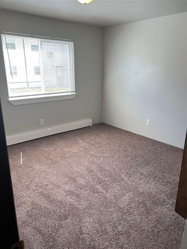 carpeted spare room featuring a baseboard heating unit