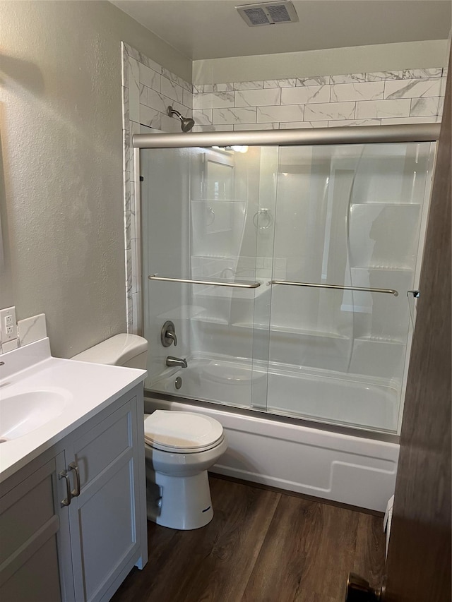 full bathroom with shower / bath combination with glass door, toilet, vanity, and hardwood / wood-style flooring