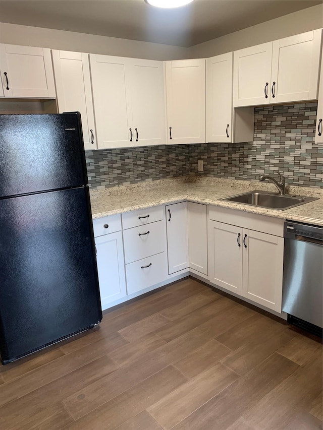 kitchen featuring stainless steel dishwasher, black fridge, white cabinetry, and sink