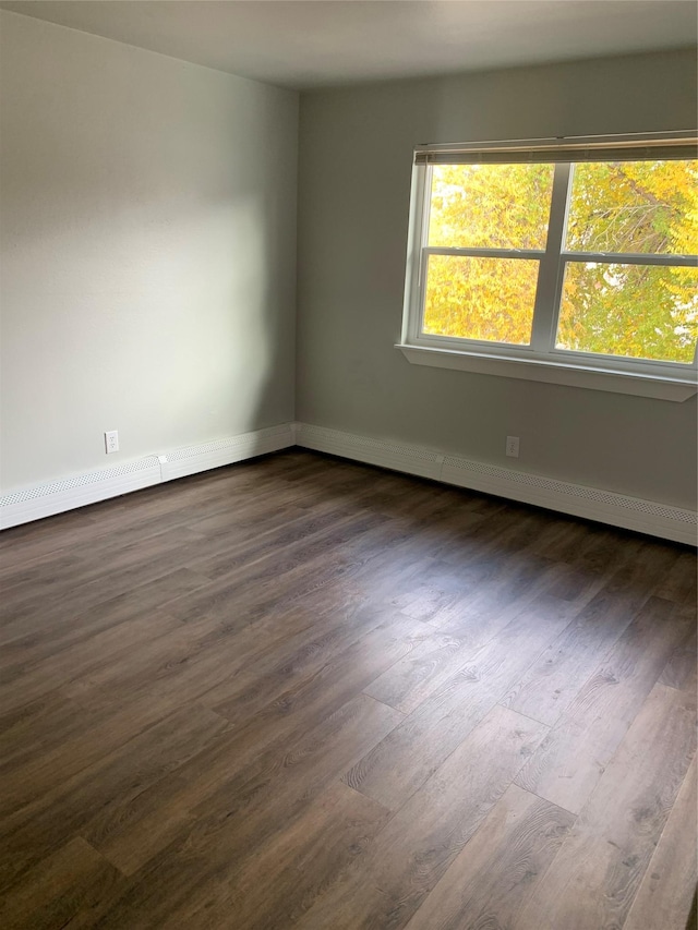 unfurnished room with baseboard heating and dark wood-type flooring