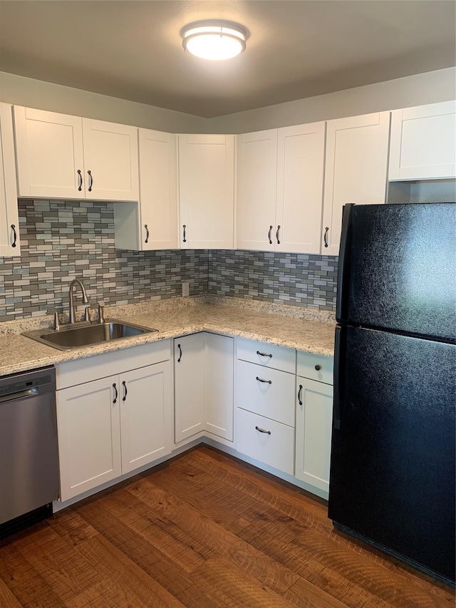 kitchen with white cabinets, black fridge, sink, stainless steel dishwasher, and dark hardwood / wood-style flooring