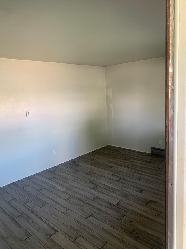 spare room with dark hardwood / wood-style flooring and a baseboard radiator