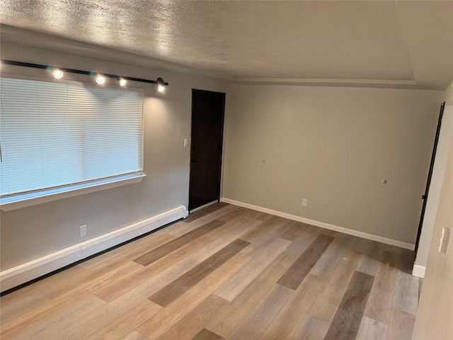 spare room featuring baseboard heating, a textured ceiling, and light wood-type flooring