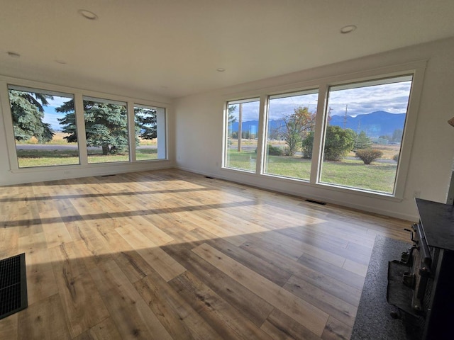 unfurnished living room featuring light wood-type flooring and a mountain view