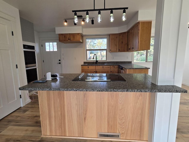 kitchen with black electric stovetop, double oven, pendant lighting, dark hardwood / wood-style floors, and sink