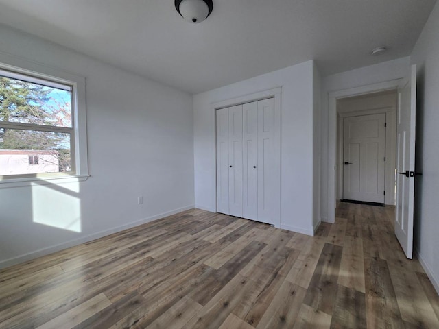 unfurnished bedroom with light wood-type flooring and a closet