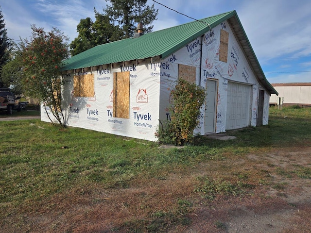 view of side of property featuring a lawn, a garage, and an outdoor structure