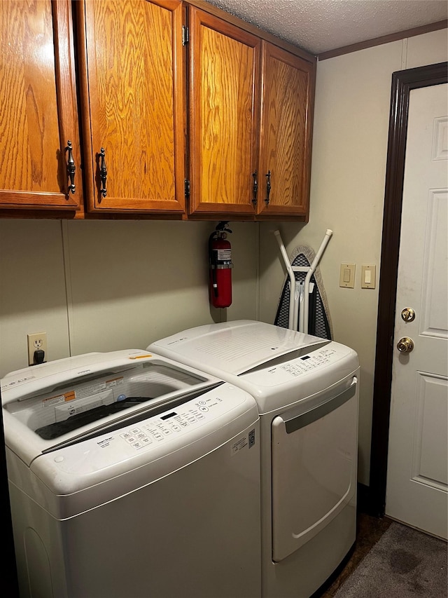 washroom featuring cabinets, a textured ceiling, and washer and dryer