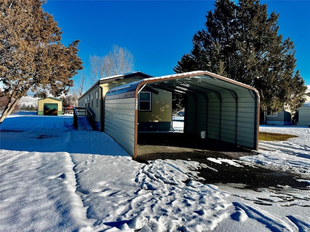 snow covered property featuring an outbuilding and a carport