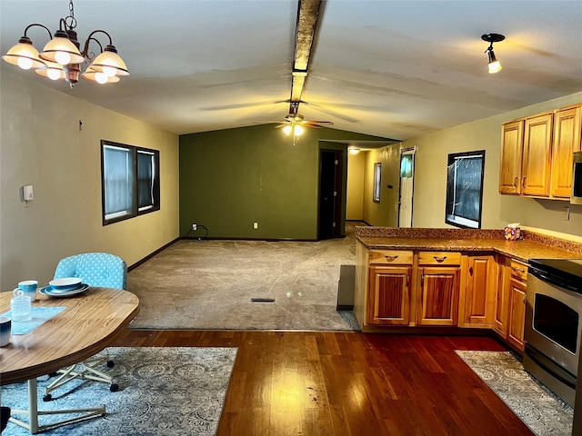 kitchen with hanging light fixtures, dark hardwood / wood-style flooring, kitchen peninsula, lofted ceiling, and appliances with stainless steel finishes