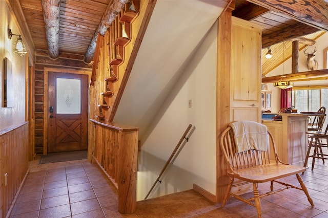 stairway featuring wooden walls, wooden ceiling, and beamed ceiling